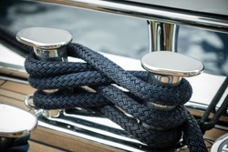Mooring lines wrapped around a big stainless steel cleat of a superyacht at dock
