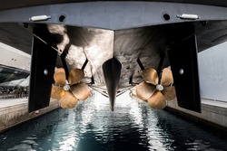 Superyacht being lowered into the water after winter haul out at shipyard, with freshly auti-fauled hull and polished propellers about to touch the water 