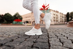 Fashionable white sneakers on female legs, close-up.