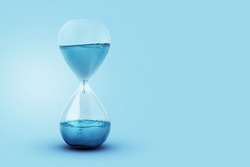 Time as water, a concept. Water with a drip dripping in a glass clock. Creative idea, save the water on a blue background. Global Warming