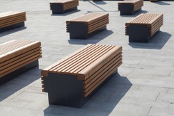 Modern benches in the city square on a sunny day. City improvement, urban planning, public spaces.