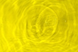 Yellow water oil texture, yellow lemon water surface with rings and ripples. Spa concept background. Flat lay, copy space.