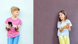 Trendy hipster kids using mobile phones while keeping social distance – Modern children having fun outdoor watching video on smartphones – Digitally happy Gen z boy and girl sharing content online