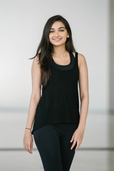 Close up portrait of a beautiful, young attractive and elegant Indian Asian woman against a white background. She is in exercise attire and is smiling confidently. 