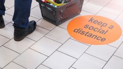 the inscription on the floor of the supermarket: keep a social distance. Selective focus