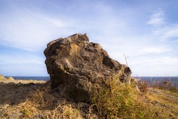 Rock overlooking the sea in Antique, Philippines, an iconic landmark. Blue sky and grass.
