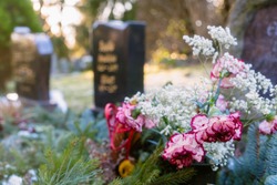 Colorful Flowers in front of a Tombstones in a Cemetery Graveyard