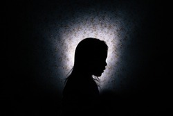 Silhouette of a little girl in the dark.