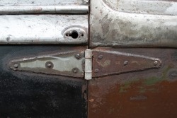 A creative, do-it-yourself door hinge on a rusty, antique car that's being restored.