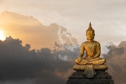 A peaceful superimposed and double exposure images of Golden Buddha statue from Wat Pathum Wanaram, Bangkok, Thailand and pink clouds. Buddha statue is posing “The attitude of subduing Mara