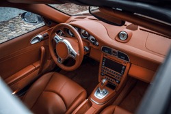 Supercar interior, view through the sunroof. Close-up view of expensive car interior with comfortable leather seats and dashboard 