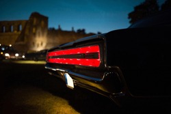 Taillight of old classic muscle car is switched on at the night