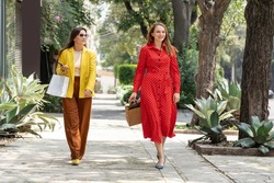 Two happy Caucasian women shopping in the city carrying bags of their purchases