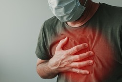 Covid-19 chest pain as infection symptom, man with respiratory mask holding a hand at his chest