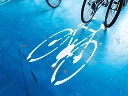Bicycle parking area with bike pictogram symbol on ground and wheels in the background