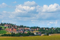 Beautiful picturesque Zlatibor region landscape with distinctive architectural style houses scattered over green hills on sunny summer day