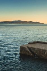 Concrete stairs and stone pier at town of Lovran in Kvarner gulf of Adriatic sea at sunset