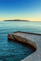 Concrete stairs and stone pier at town of Lovran in Kvarner gulf of Adriatic sea at sunset