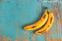 Two old ripe bananas on rustic wooden table, top view