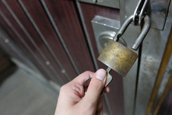 Unlocking padlock on the gate of rusty metal steel