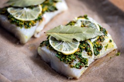 Cod fillets with coriander crust, lemon and bay leaf prepared for baking