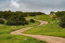 A nature path going through fields and hills in the Adullam region of Israel, on an overcast day.