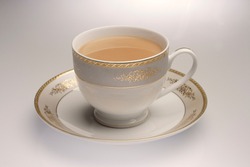 Masala Tea Chai hot in a ornate golden cup with saucer on a wooden background
