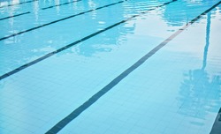 Calm water on empty swimming pool, dark lanes marks visible floor