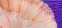 Fragment pair of colorful ballet tutus.Abstract close-up selective focus peach and purple mesh.circle segment.Folds,curls of fabric in small stitch.Horizontal banner,wall paper,textured background