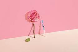 Creative concept of botox beauty injections. Syringe with toxin and rose on pastel background