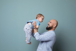 Portrait of dad and his little son on color background