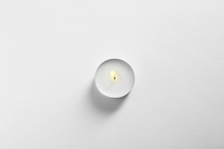 Burning wax candle on white background, top view
