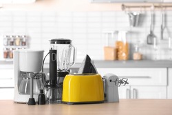 Household and kitchen appliances on table against blurred background