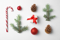 Composition with Christmas tree branches, festive decor and gift box on white background