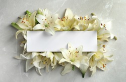 Flat lay composition with lily flowers and blank card on light background