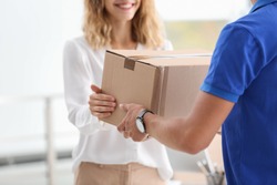 Young woman receiving parcel from courier indoors