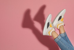 Woman in stylish sneakers near color wall, closeup. Space for text