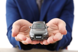 Insurance agent holding toy car over table, focus on hands