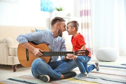 Father playing guitar for his son at home