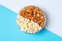 Different kinds of popcorn in bowl on color background, top view