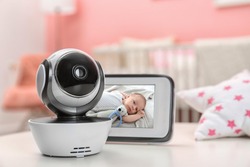 Modern security CCTV camera and monitor with baby's image on table. Space for text