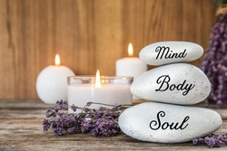 Composition of lavender flowers and zen stones with words Mind, Body, Soul on table against  wooden background. Space for text 