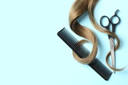 Flat lay composition with light brown hair, comb, scissors and space for text on color background. Hairdresser service