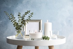Composition with burning aromatic candles on table near color wall