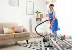 Woman hoovering carpet in living room. Cleaning service