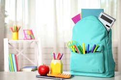 Bright backpack and school stationery on table indoors, space for text