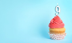 Birthday cupcake with number nine candle on blue background, space for text