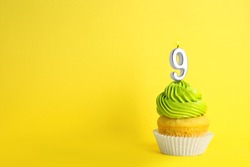 Birthday cupcake with number nine candle on yellow background, space for text