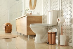 Toilet bowl near wooden screen in modern bathroom interior