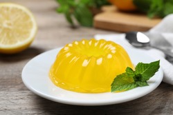Delicious fresh yellow jelly with mint on wooden table